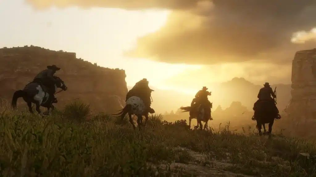 Des cavaliers traversent une vallée au coucher du soleil dans Red Dead Redemption 2